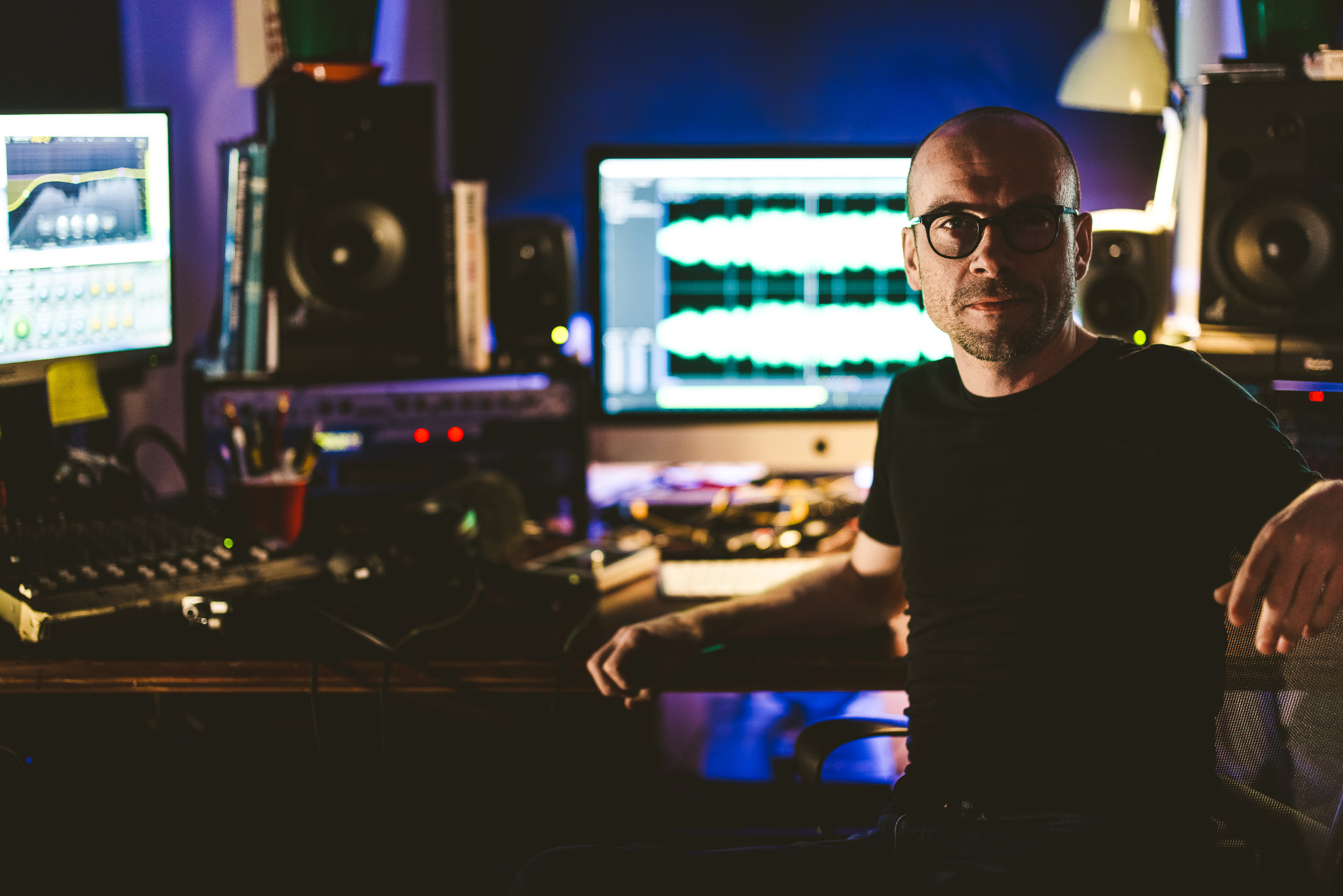 Chris Bailey at his studio desk, waveforms on screen behind him